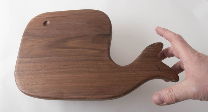 Hand reaching for Whale Charcuterie board, in walnut